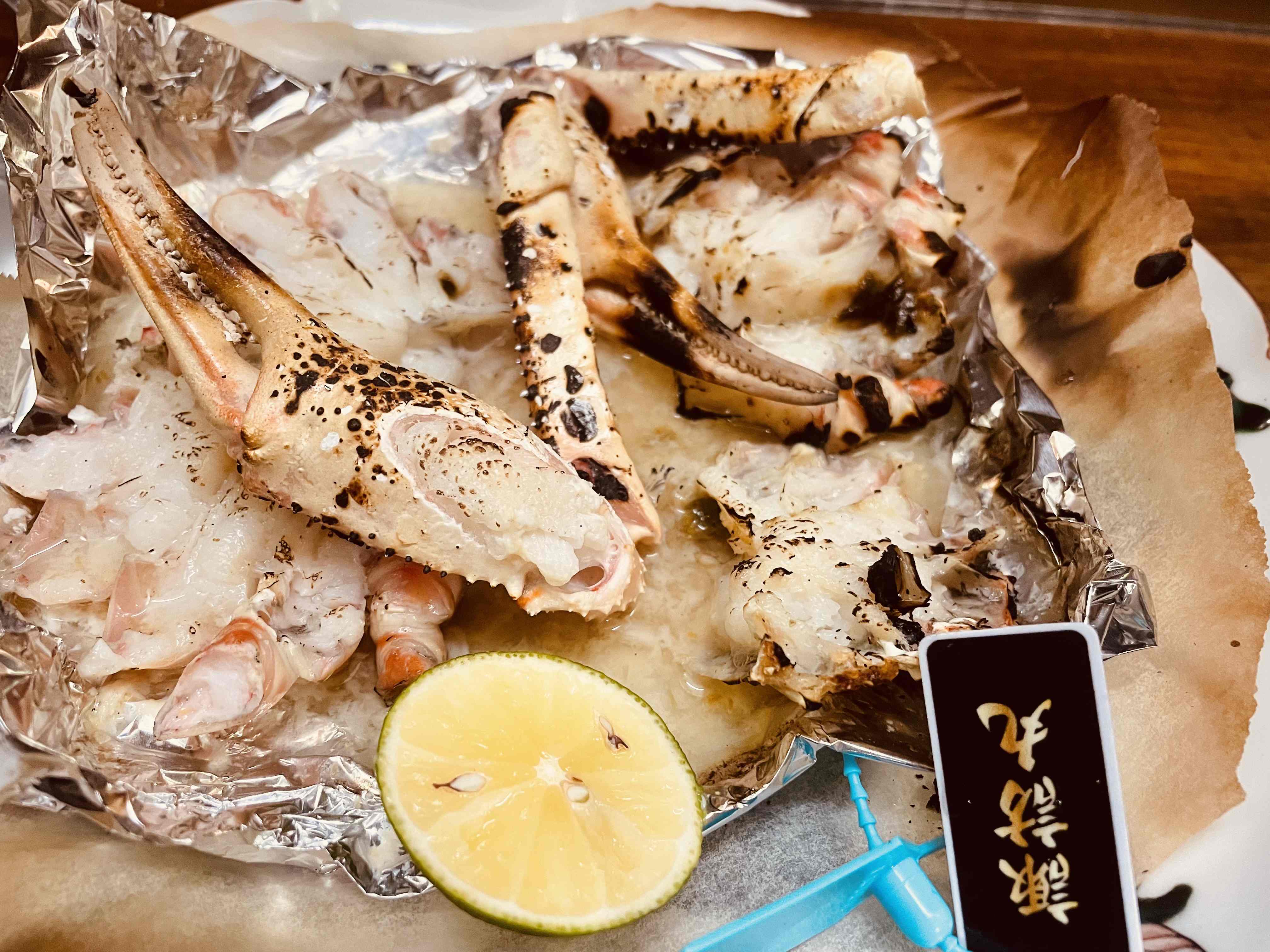 プチホテル アイビーの本ずわい蟹の焼きガニ。ホイルの上で焼かれた蟹の脚とレモン